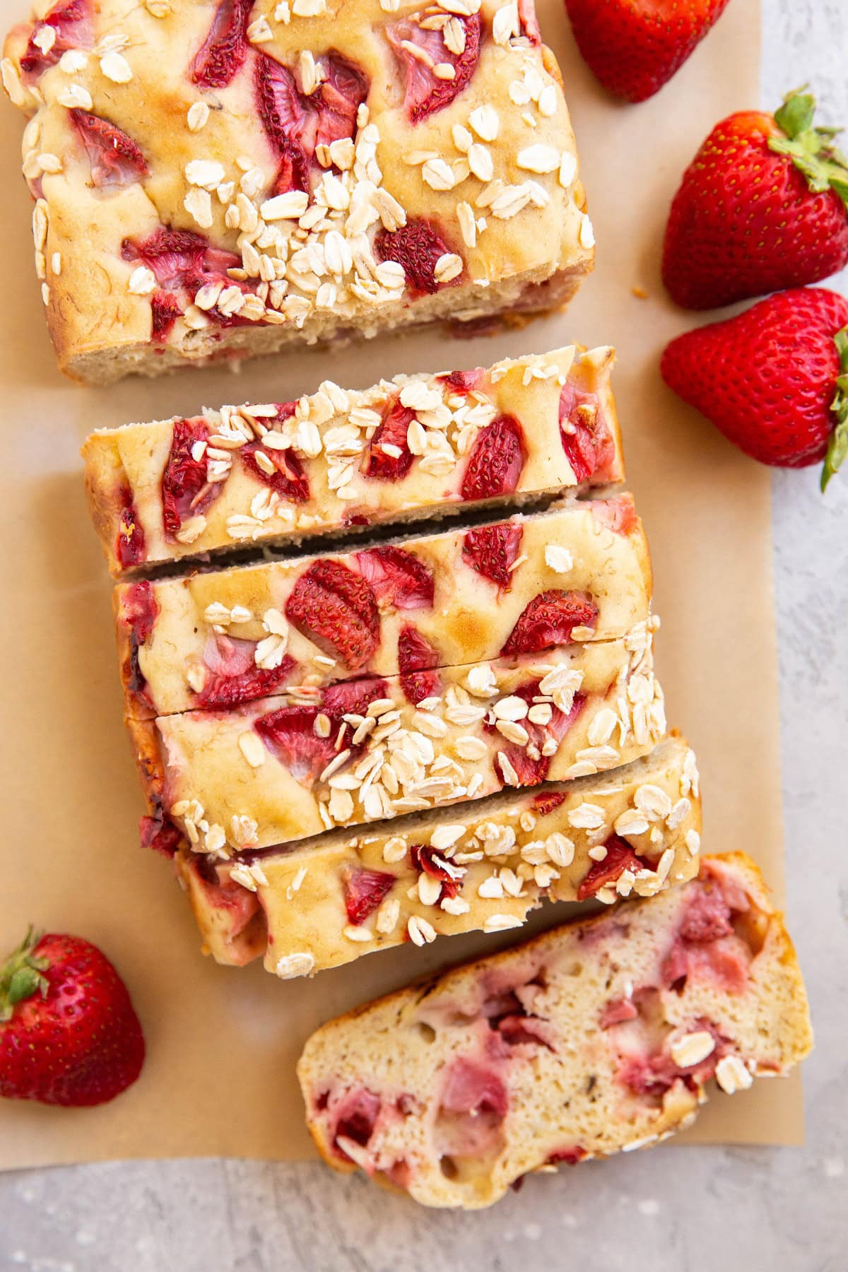 Loaf of strawberry banana bread on a sheet of parchment paper, cut into slices.