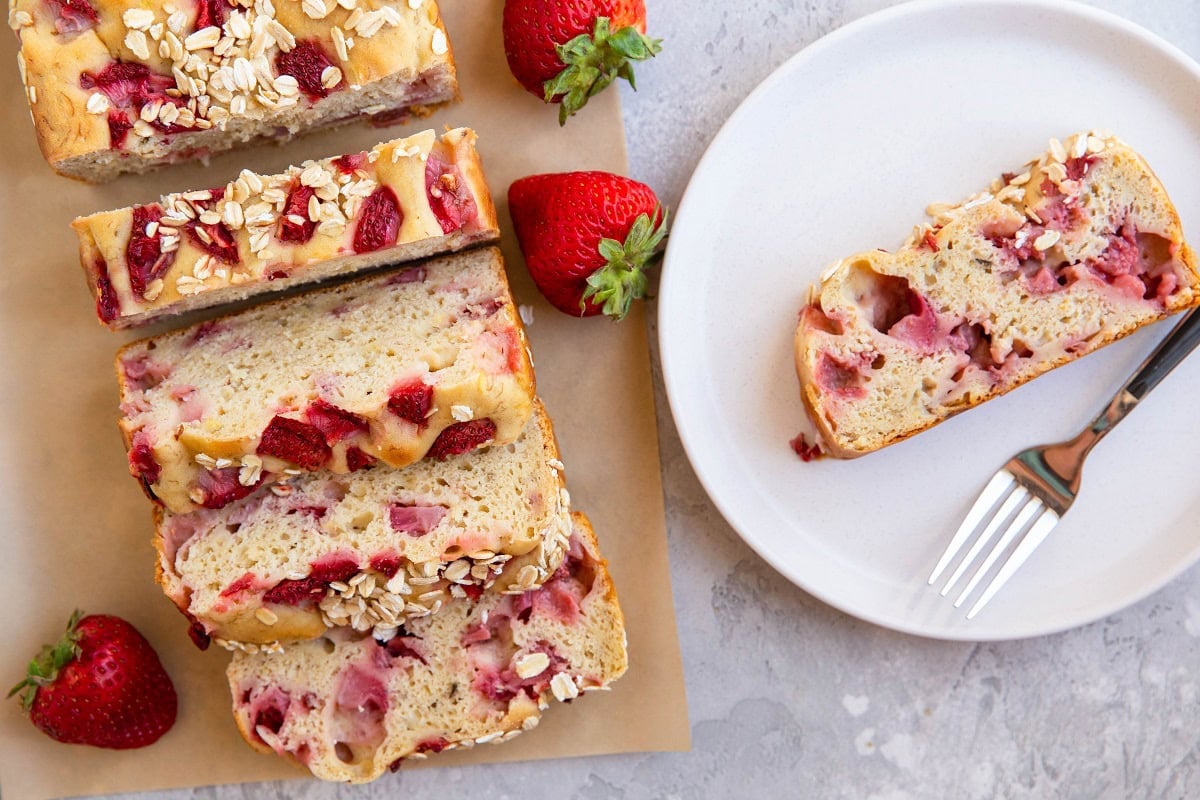 sliced loaf of banana bread on parchment paper with a slice of banana bread on a plate.