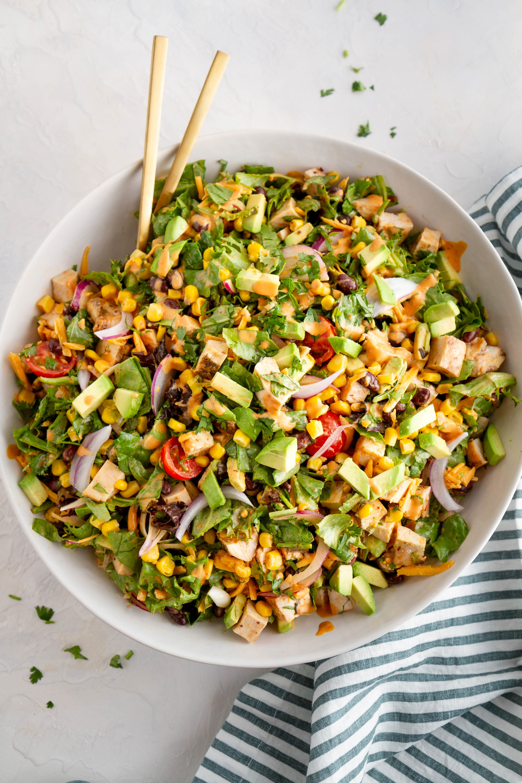 Big bowl of southwest chopped salad with serving spoons, ready to serve.