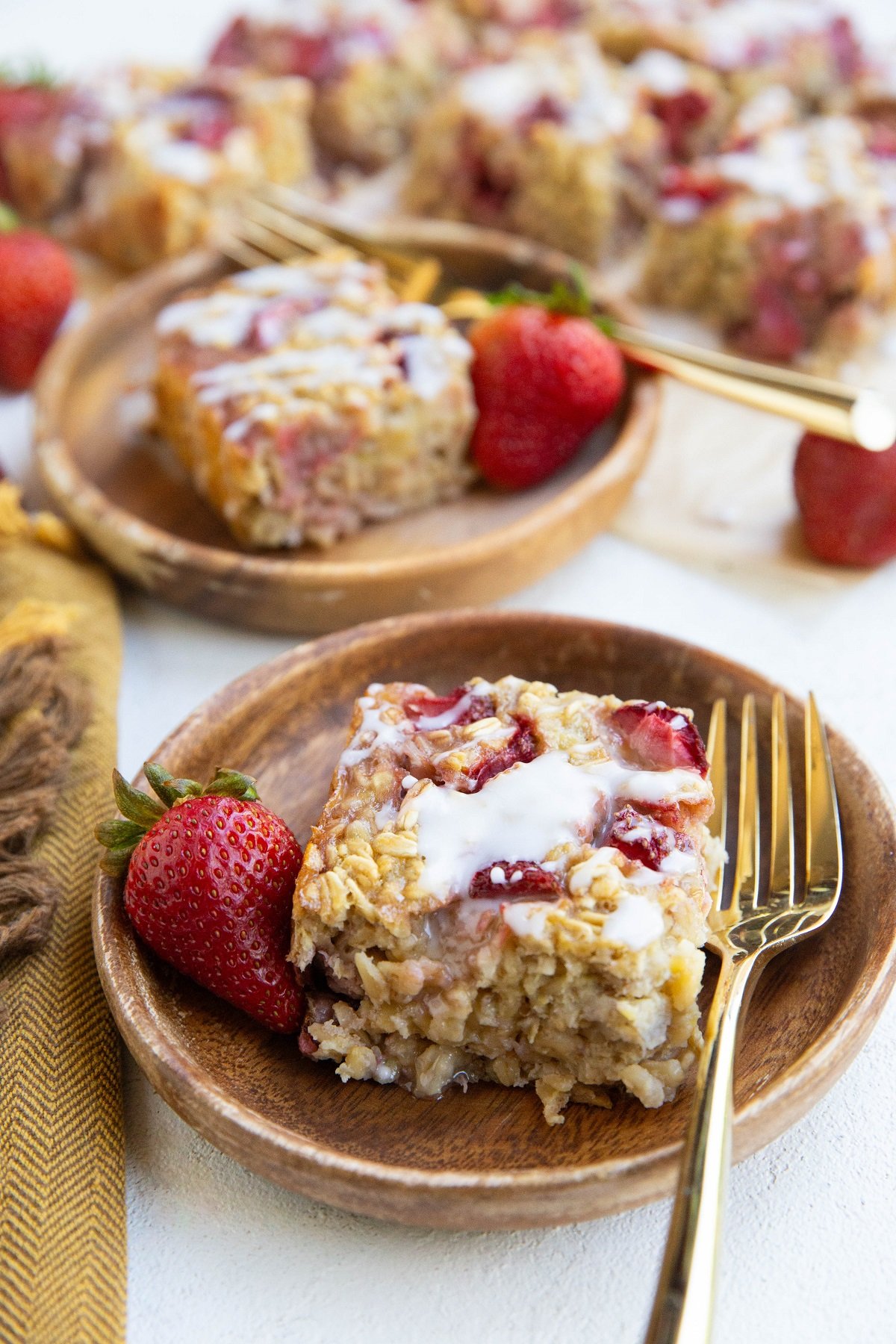 Two wooden plates of baked oatmeal with more pieces of baked oatmeal in the background.
