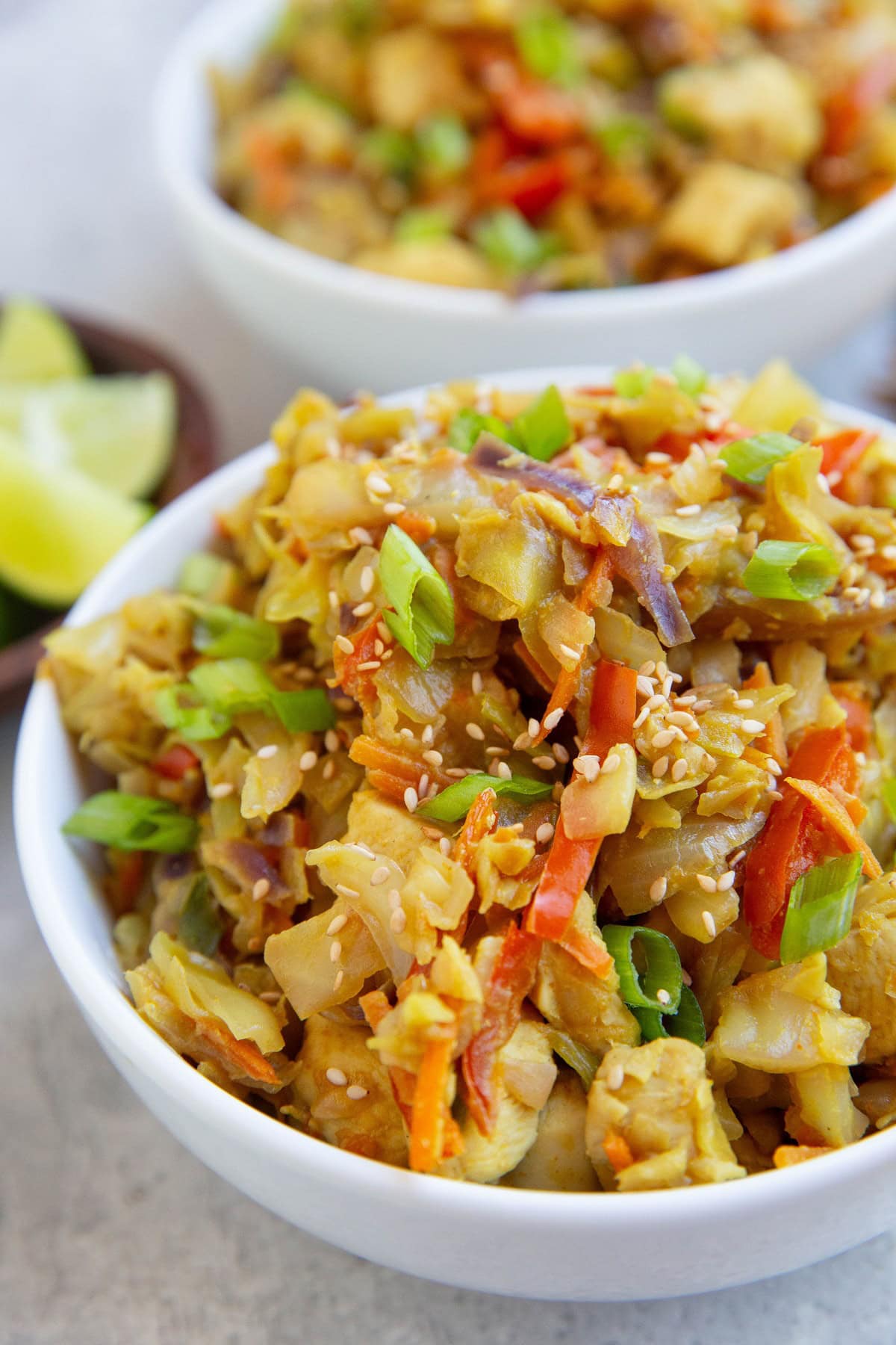 Two white bowls full of Thai cabbage and chicken.