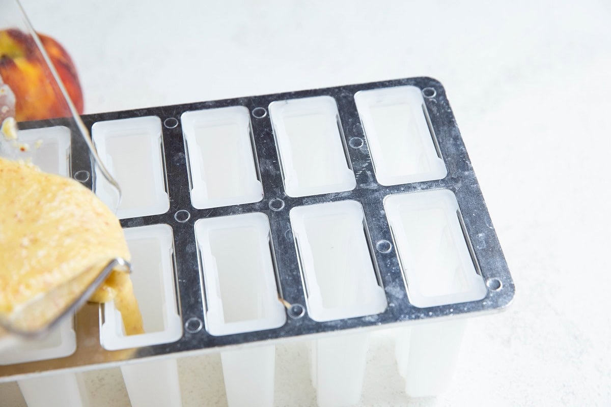 Blender pouring peach mixture into a silicone mold.