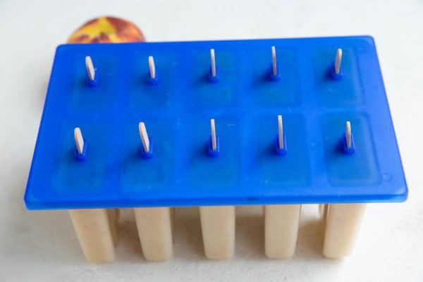 Popsicle mold full of peach popsicle mixture.