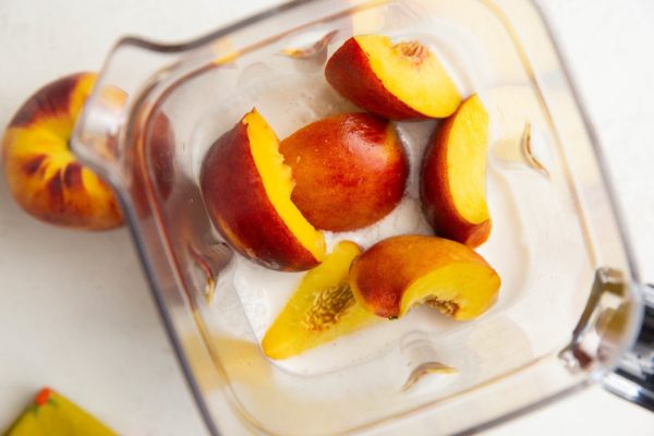 Ingredients for peach popsicles in a blender.