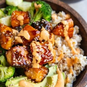 Bang bang salmon in a bowl with avocado, sauteed broccoli, and rice.