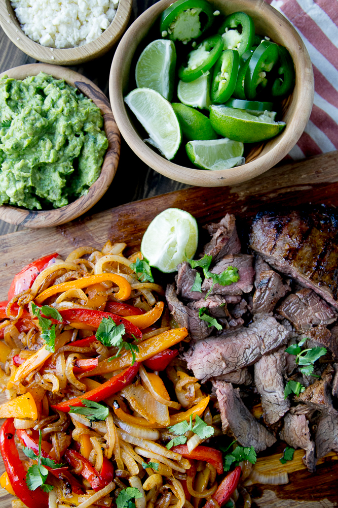 Steak fajitas and fajita vegetables on a cutting board.