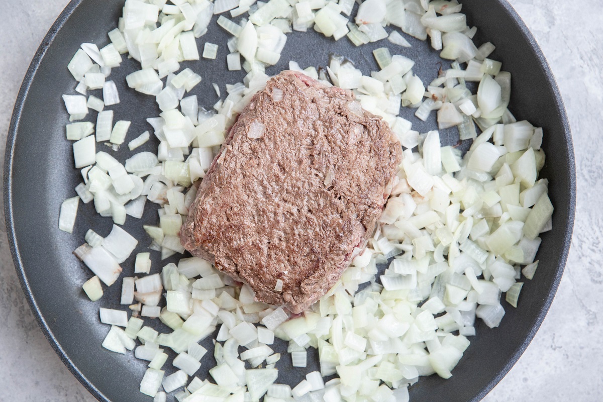 Ground beef browning in a pan with onions.