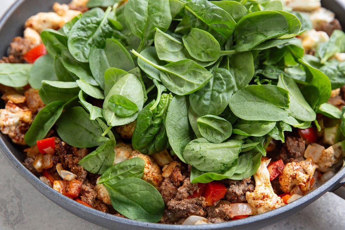 Baby spinach on top of ground beef and cauliflower.