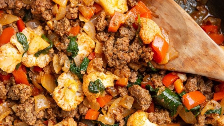 Ground beef and vegetables in a skillet with a wooden spoon, ready to serve.