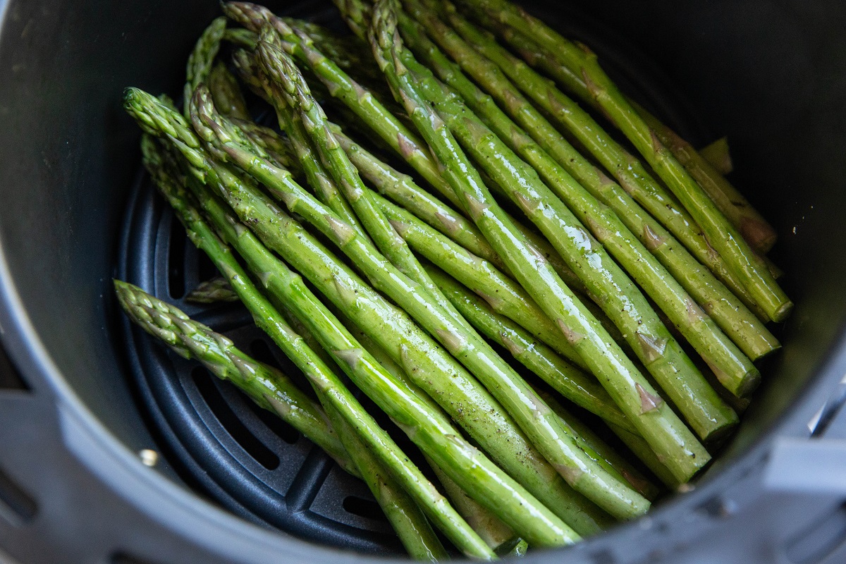 Raw asparagus in an air fryer, ready to be cooked