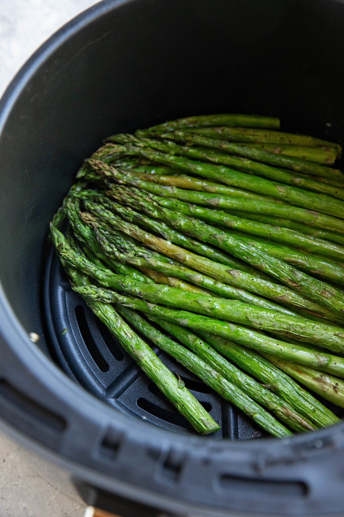 Cooked asparagus in an air fryer basket, ready to serve.