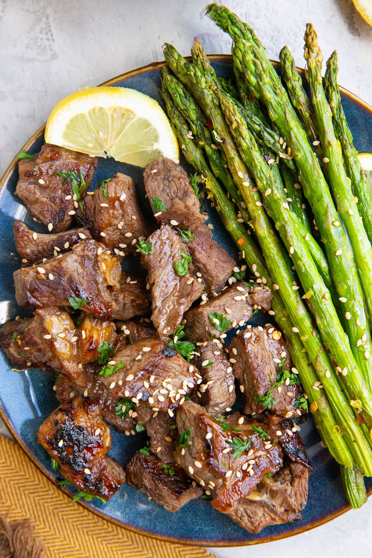 Blue plate of air fryer asparagus with steak bites, ready to eat.