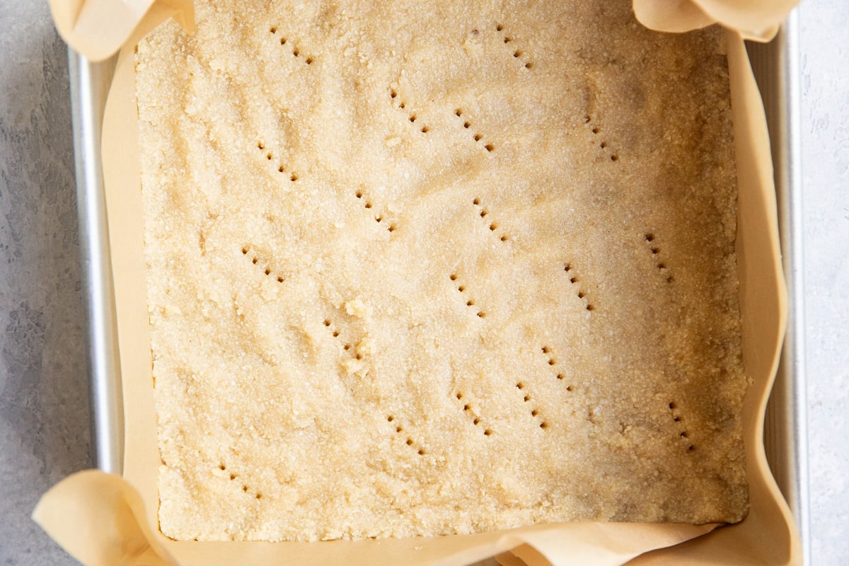 Almond flour shortbread crust in a baking pan, ready to be baked.