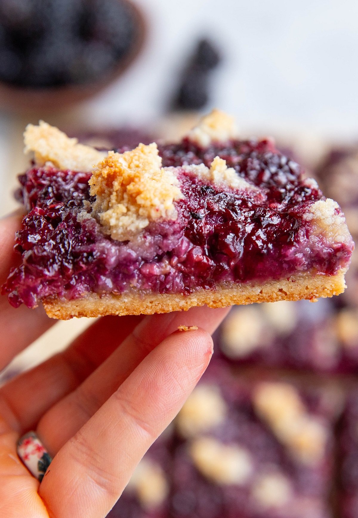 Hand holding a blackberry crumb bar.