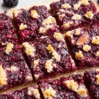 Blackberry bars cut into individual bars on a sheet of parchment paper.