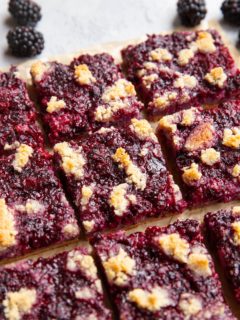 Blackberry bars cut into individual bars on a sheet of parchment paper.