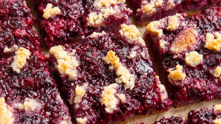 Blackberry bars cut into individual bars on a sheet of parchment paper.