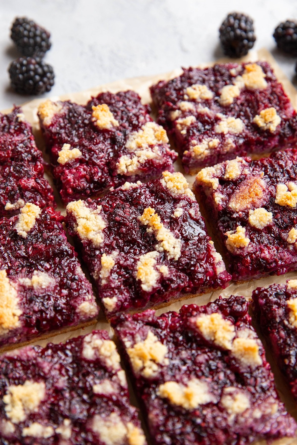 Blackberry bars cut into individual bars on a sheet of parchment paper.