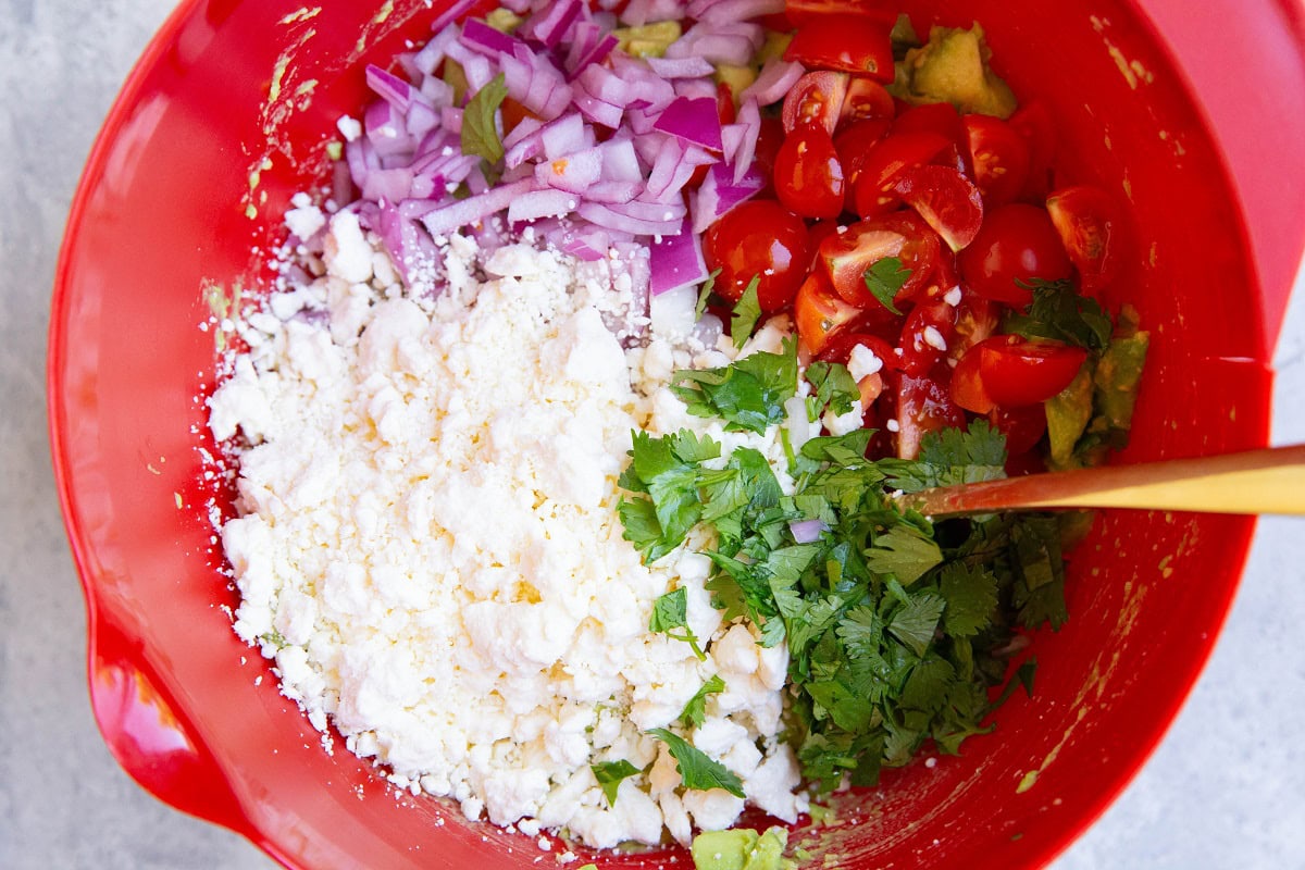 Ingredients for chunky avocado dip in a mixing bowl, ready to be mixed up.