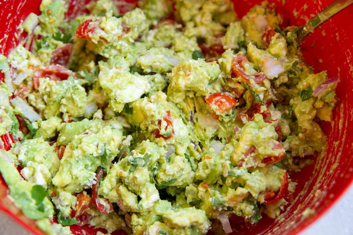 Red bowl of avocado feta dip.