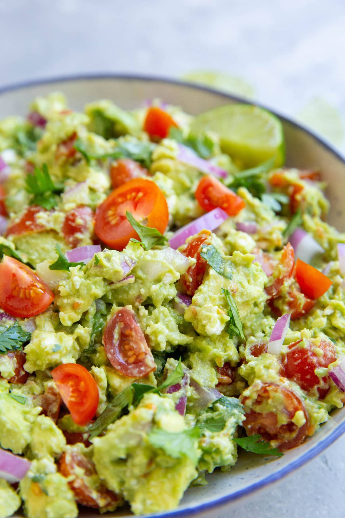 Blue rimmed bowl full of avocado dip, ready to serve.