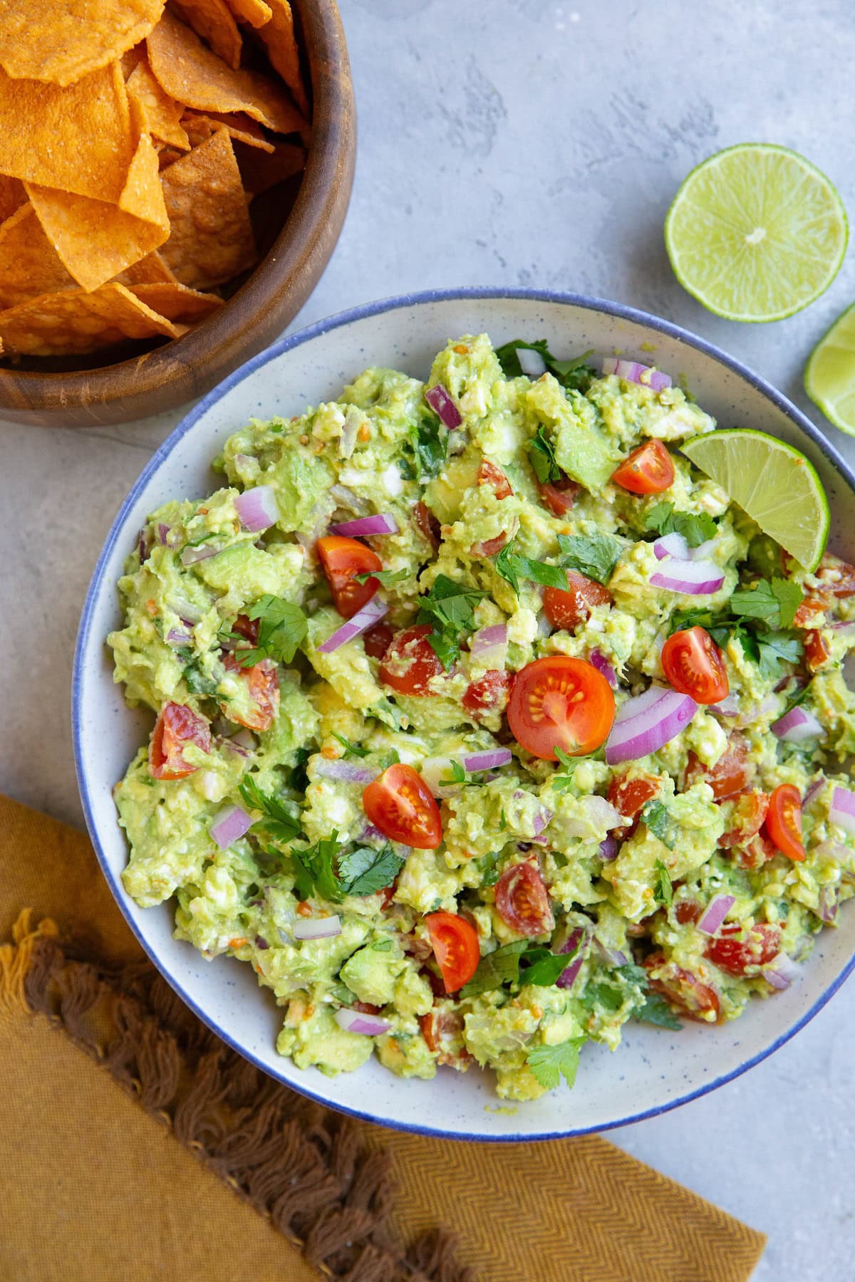 Bowl of avocado dip and bowl of chips, ready to be eaten.