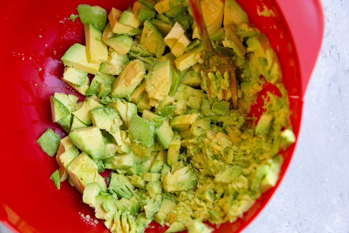 Mashing avocado in a mixing bowl for chunky avocado dip.