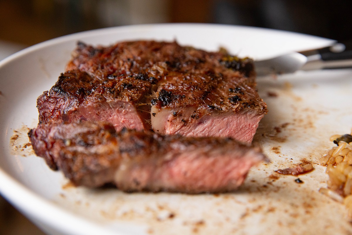 Plate of steak that has been cut into, revealing a medium doneness.