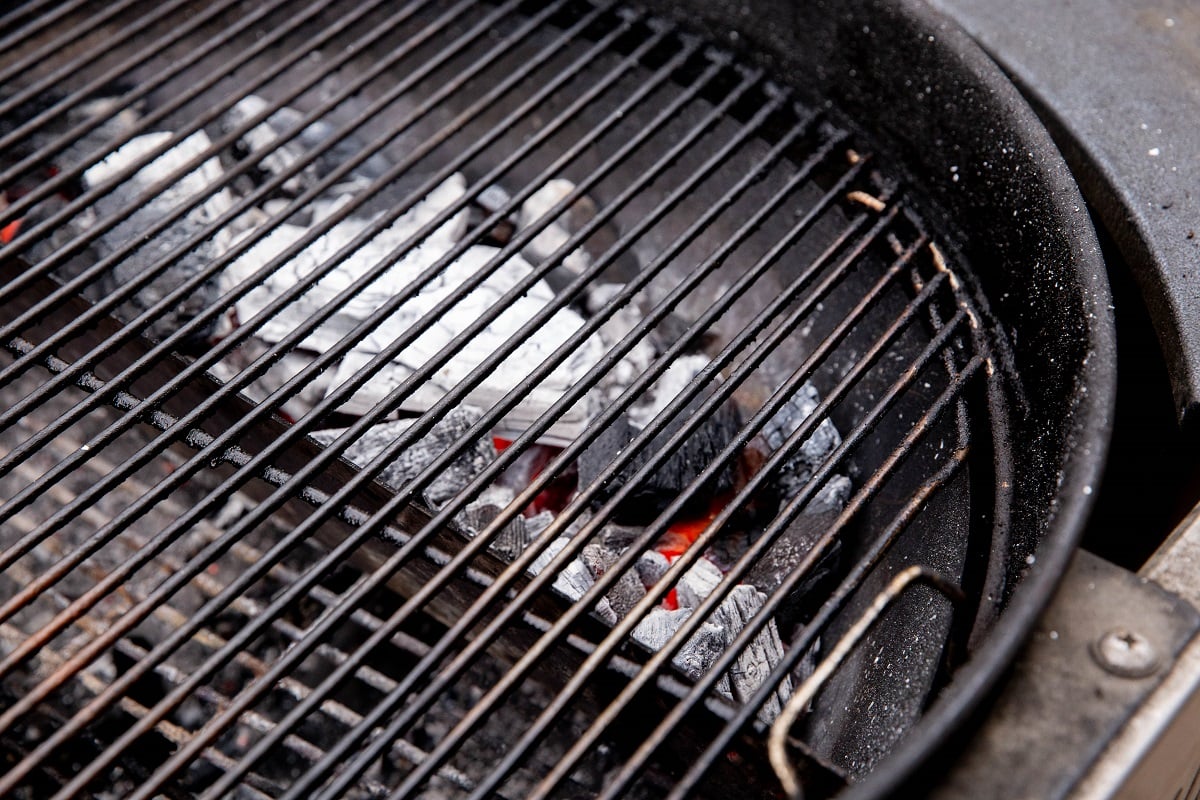 Lump charcoal in a basket in a weber grill.
