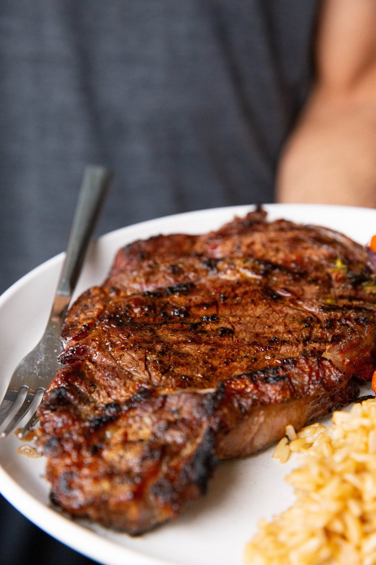 Plate of grilled ribeye steak, ready to eat.