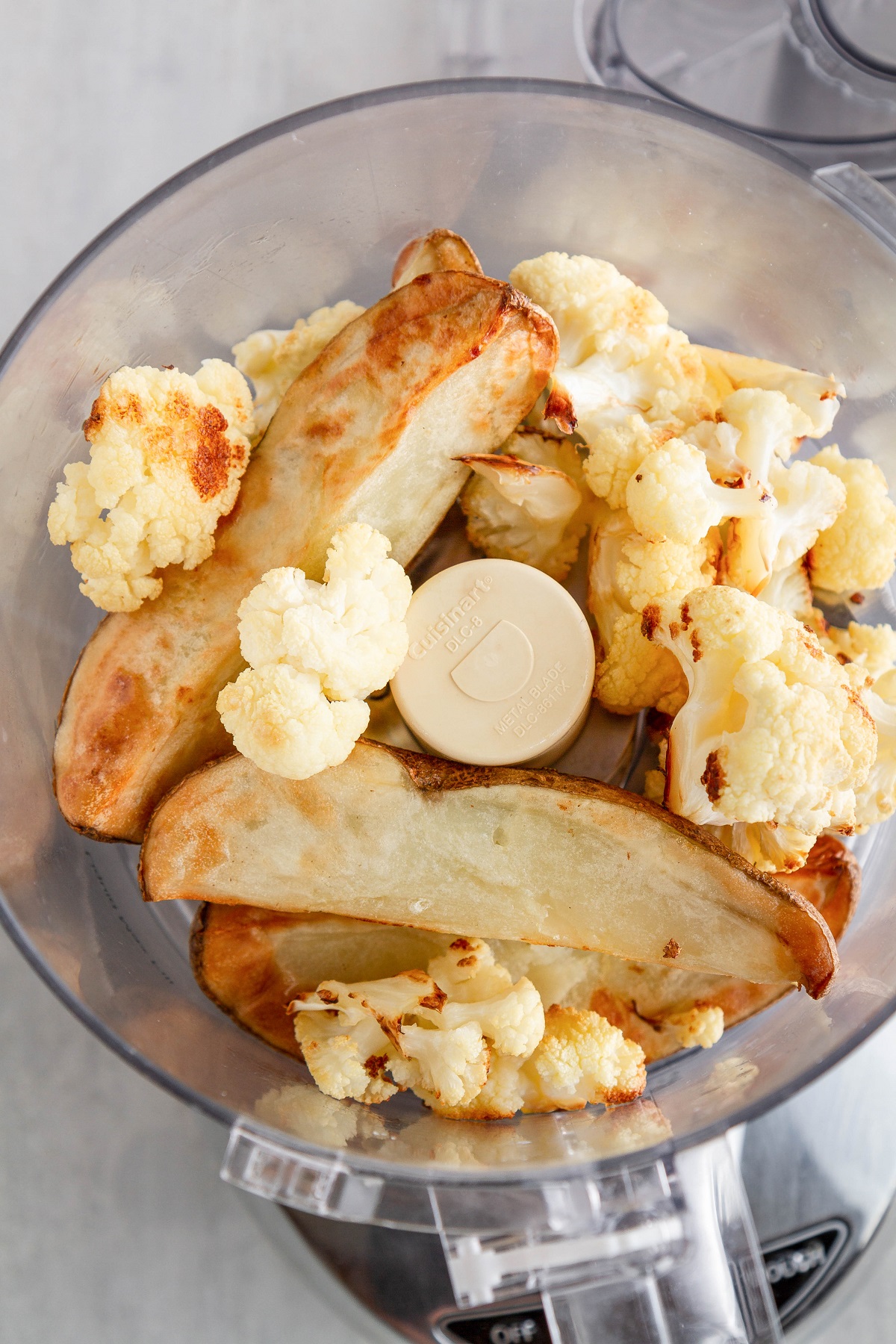 Roasted potatoes and cauliflower in a food processor, ready to be blended up for potato cakes.