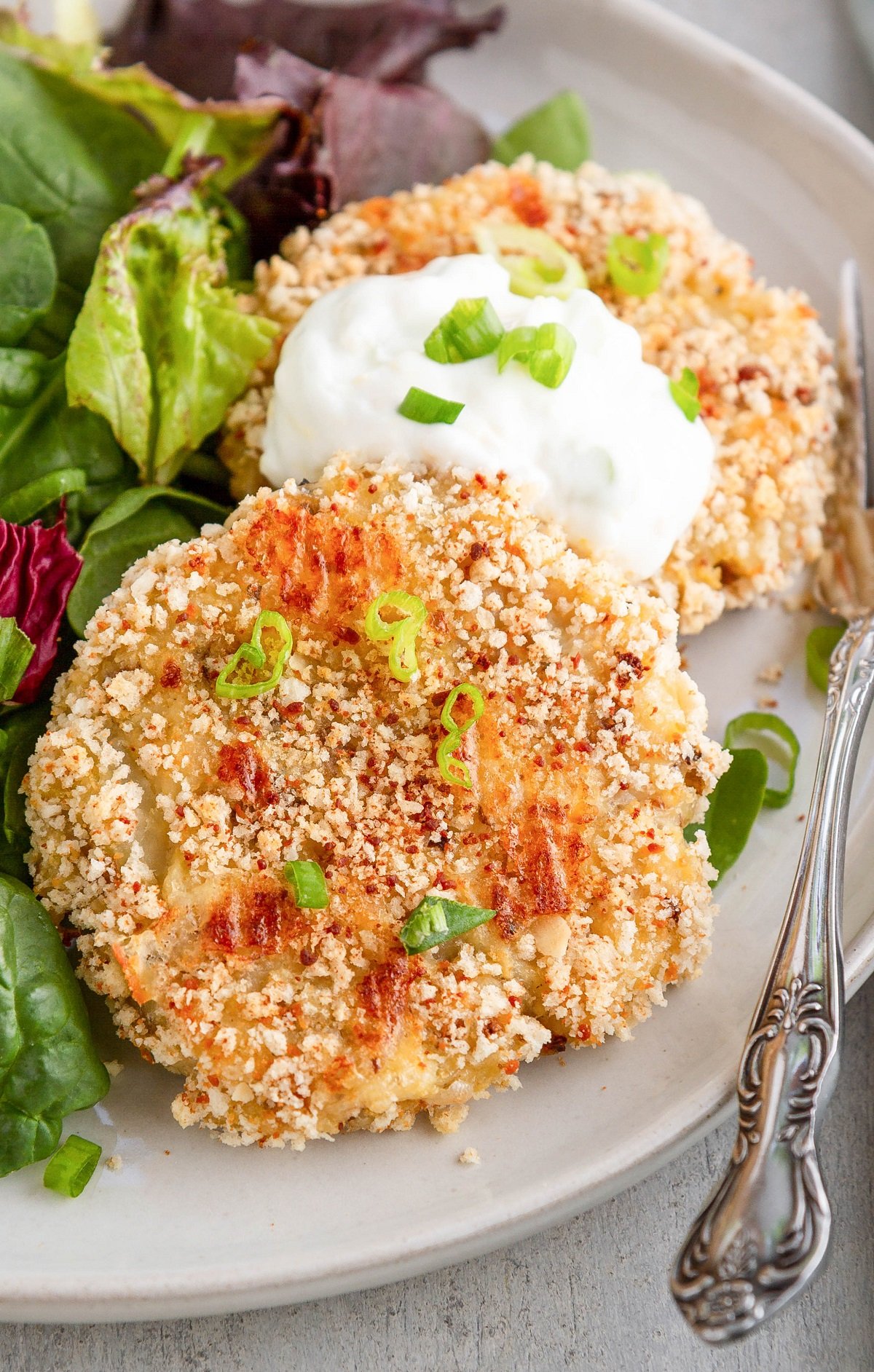 Close up image of cauliflower cakes on a plate with yogurt dipping sauce.