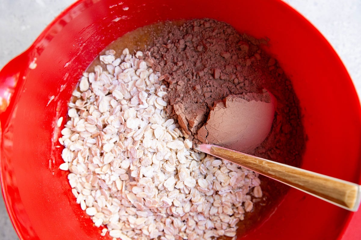 Mixing bowl with wet ingredients and cocoa powder and oats on top, ready to be mixed in.
