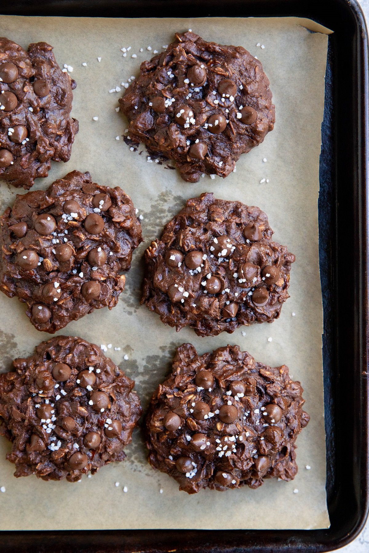 Double chocolate chip oatmeal cookies on a baking sheet, fresh out of the oven.