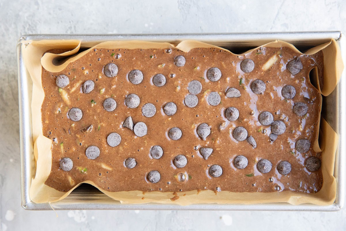 Zucchini bread batter in a parchment lined loaf pan, ready to go into the oven.