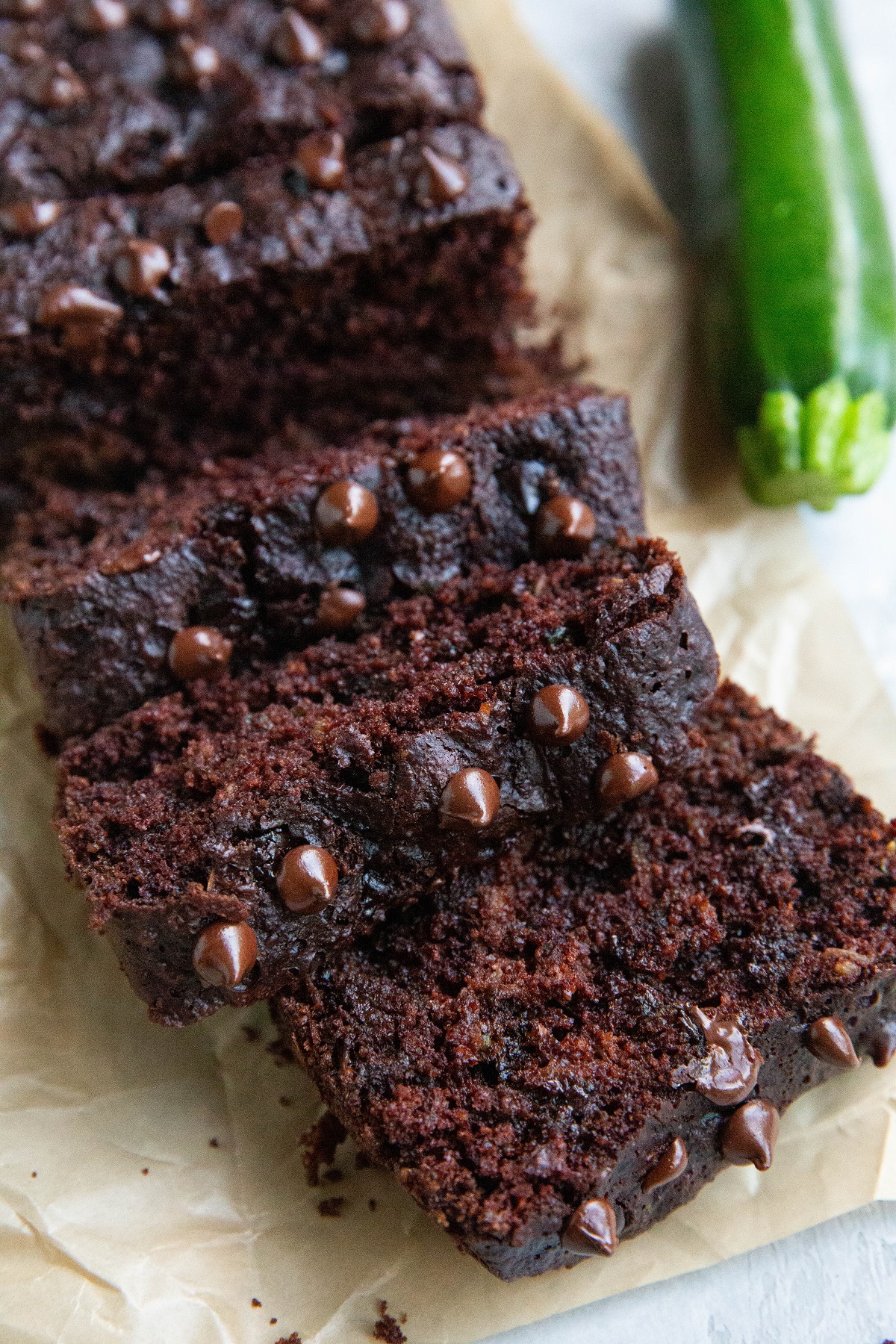 Sliced chocolate zucchini bread on a sheet of parchment paper.
