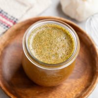 Jar of chicken marinade sitting on a wooden plate, ready to be used.