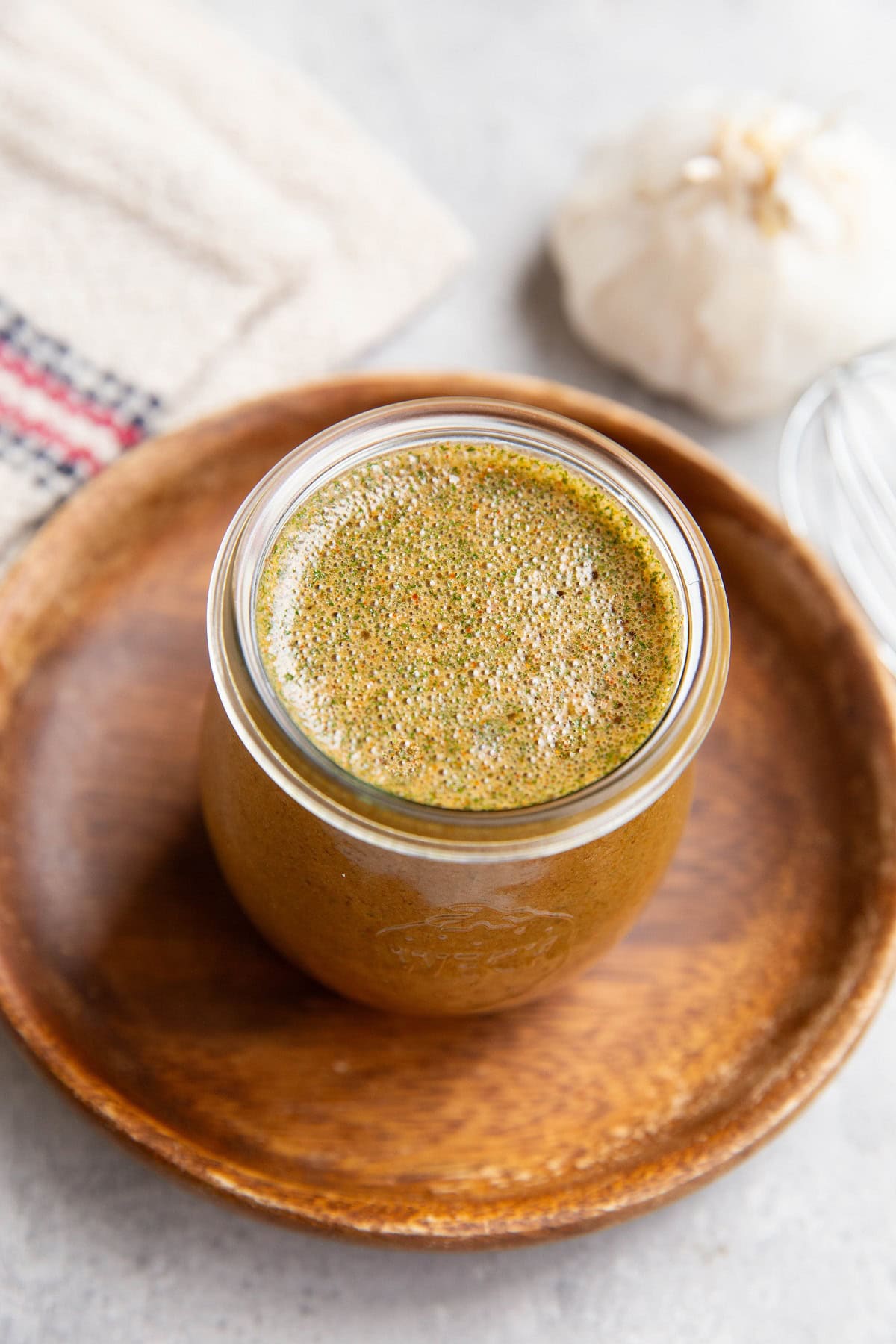 Jar of chicken marinade sitting on a wooden plate, ready to be used.