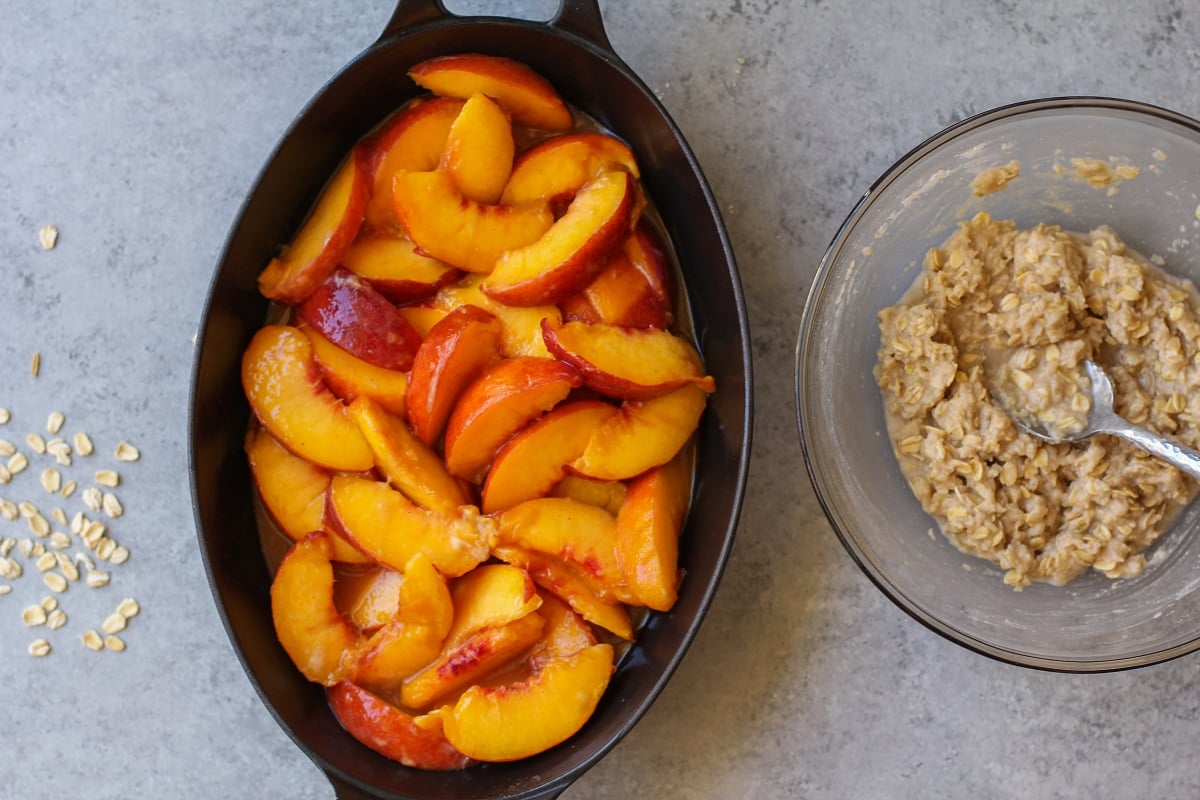 Peach filling mixture in a casserole dish and crumble topping mixture in a separate bowl.