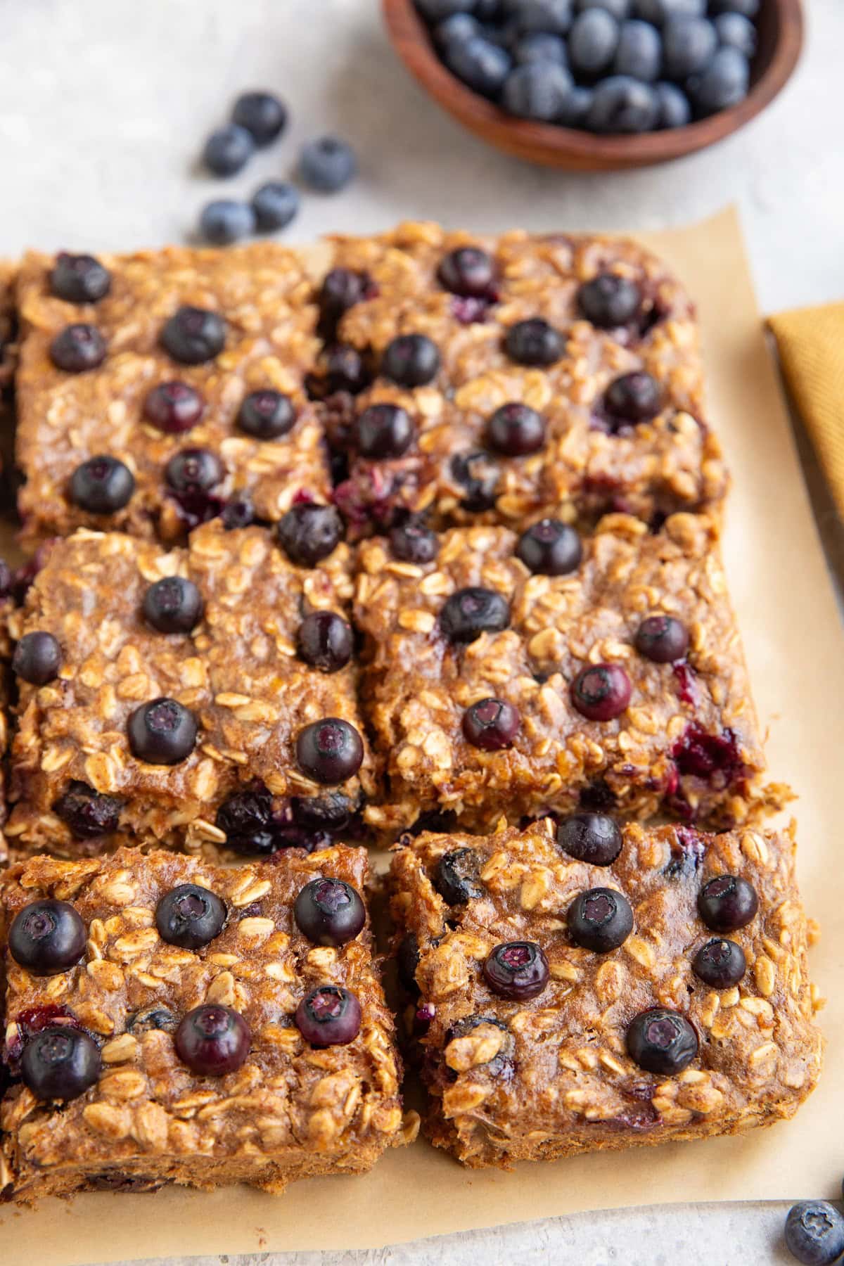 Blueberry oat bars on a sheet of parchment paper cut into slices.