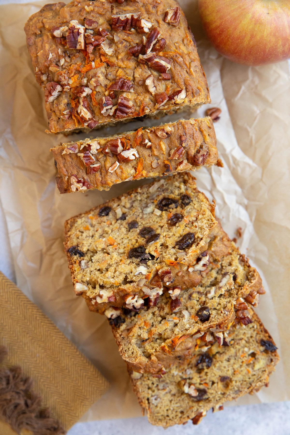 Loaf of morning glory bread on a sheet of parchment paper, cut into slices.