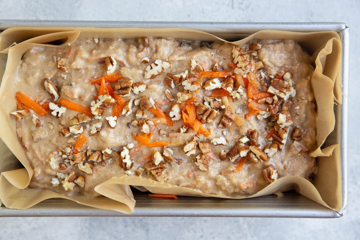 Morning glory bread batter in a prepared loaf pan, ready to be baked.