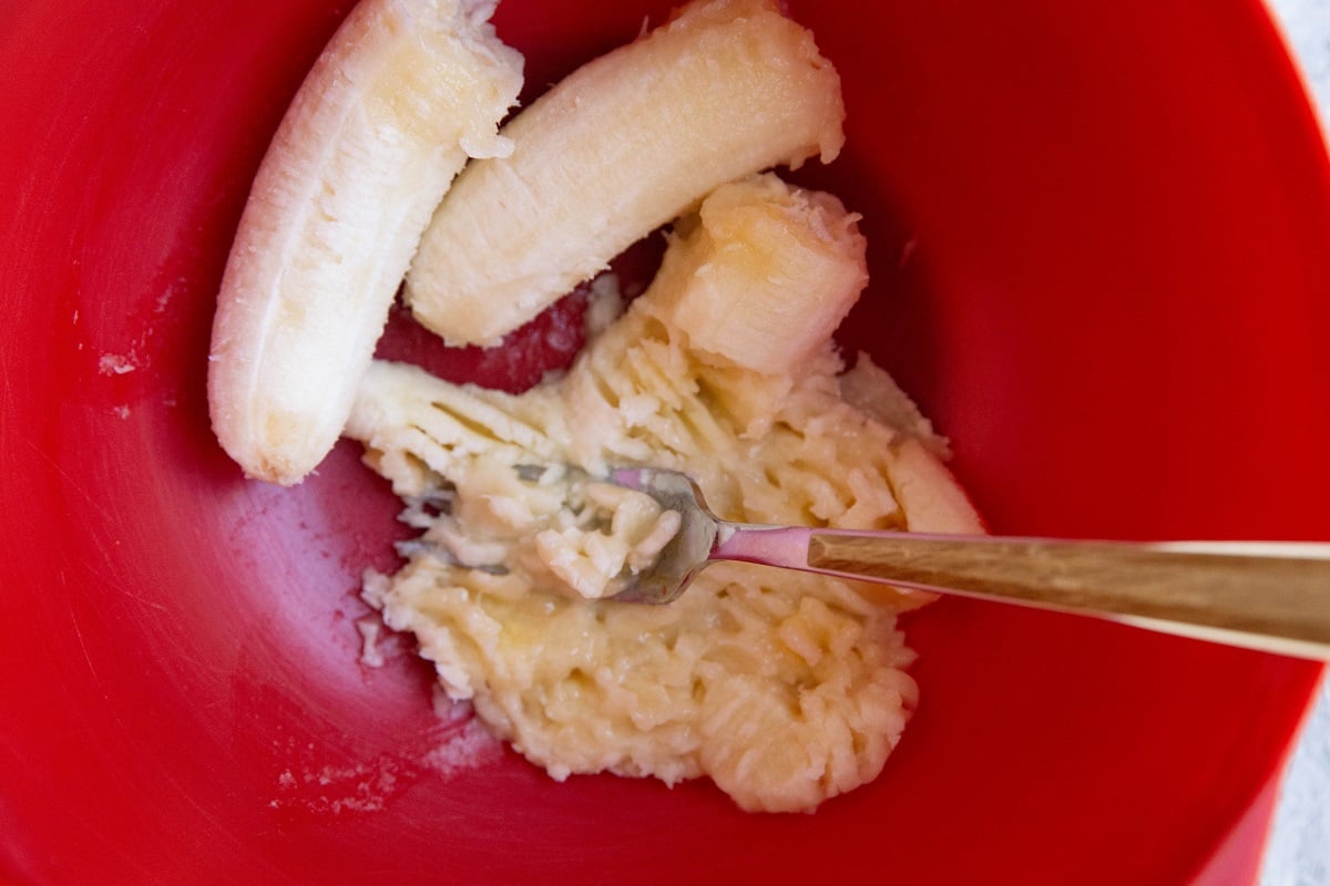 Ripe bananas being mashed in a mixing bowl for bread.