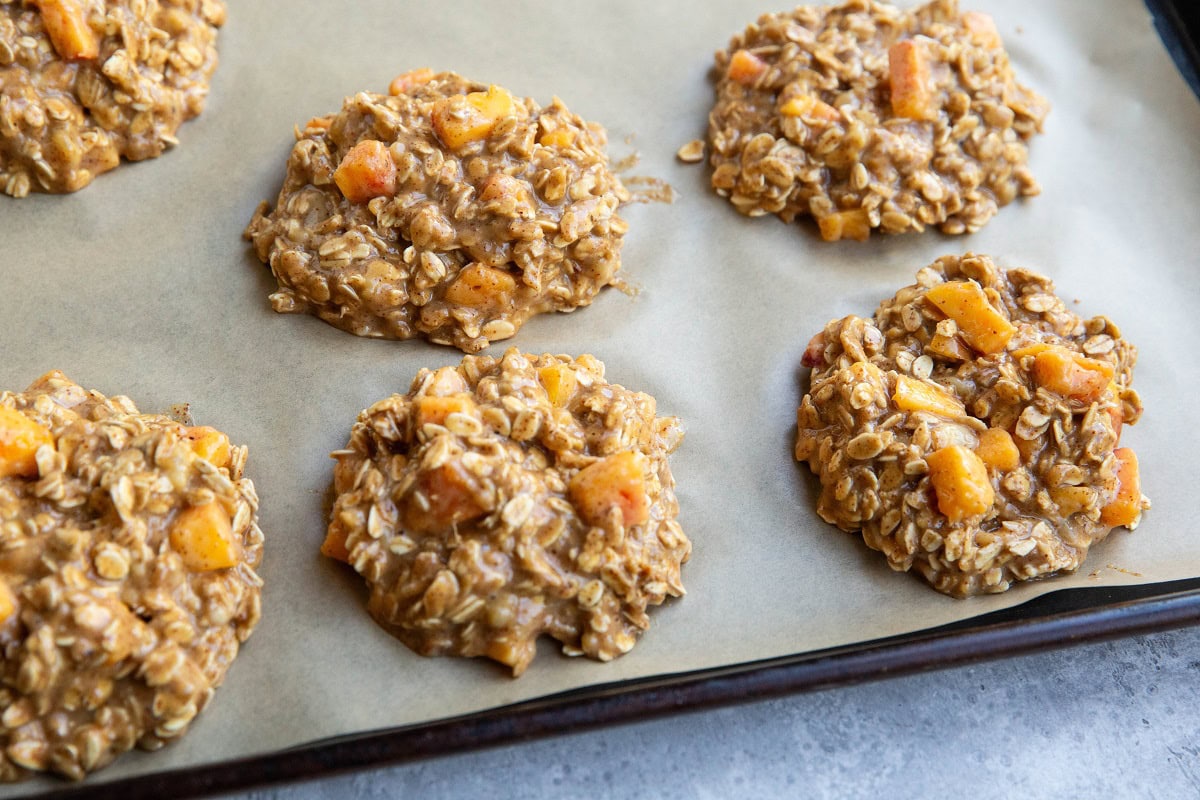 peach oatmeal cookie dough on a parchment lined baking sheet, ready to go into the oven.