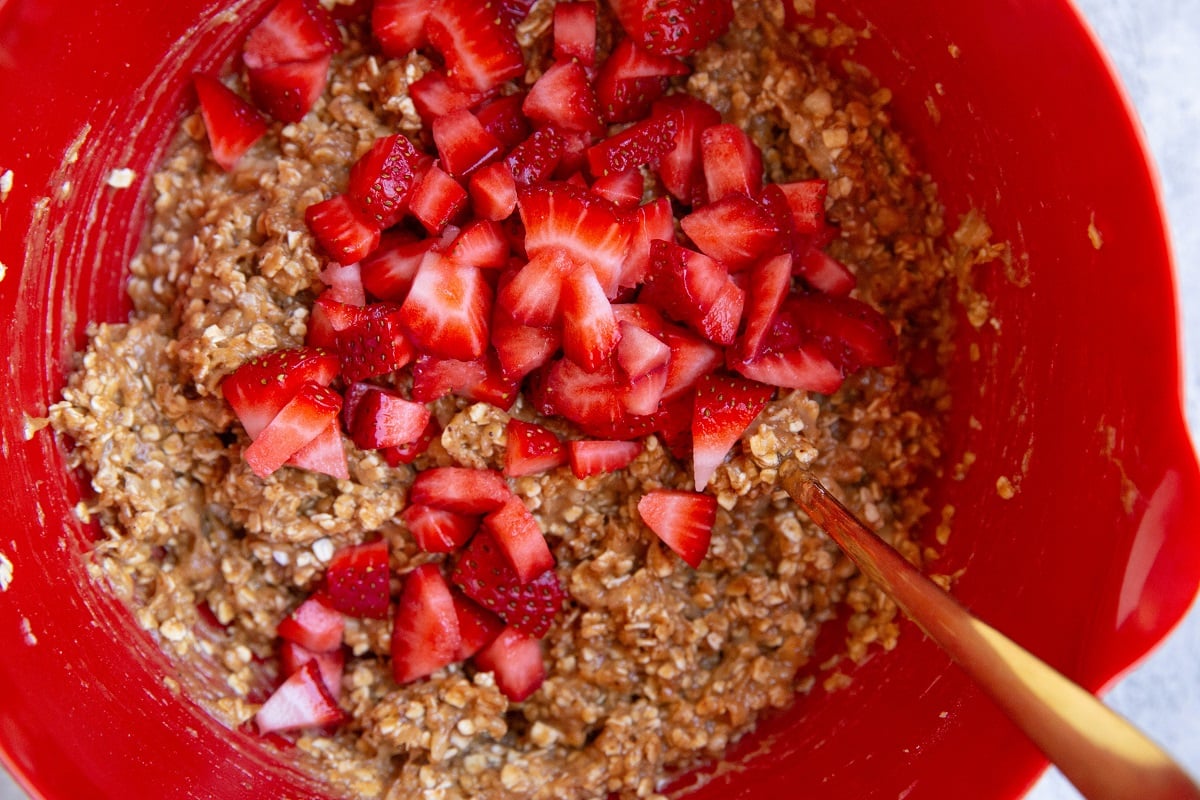Strawberry oatmeal cookie mixture with chopped strawberries in a mixing bowl.