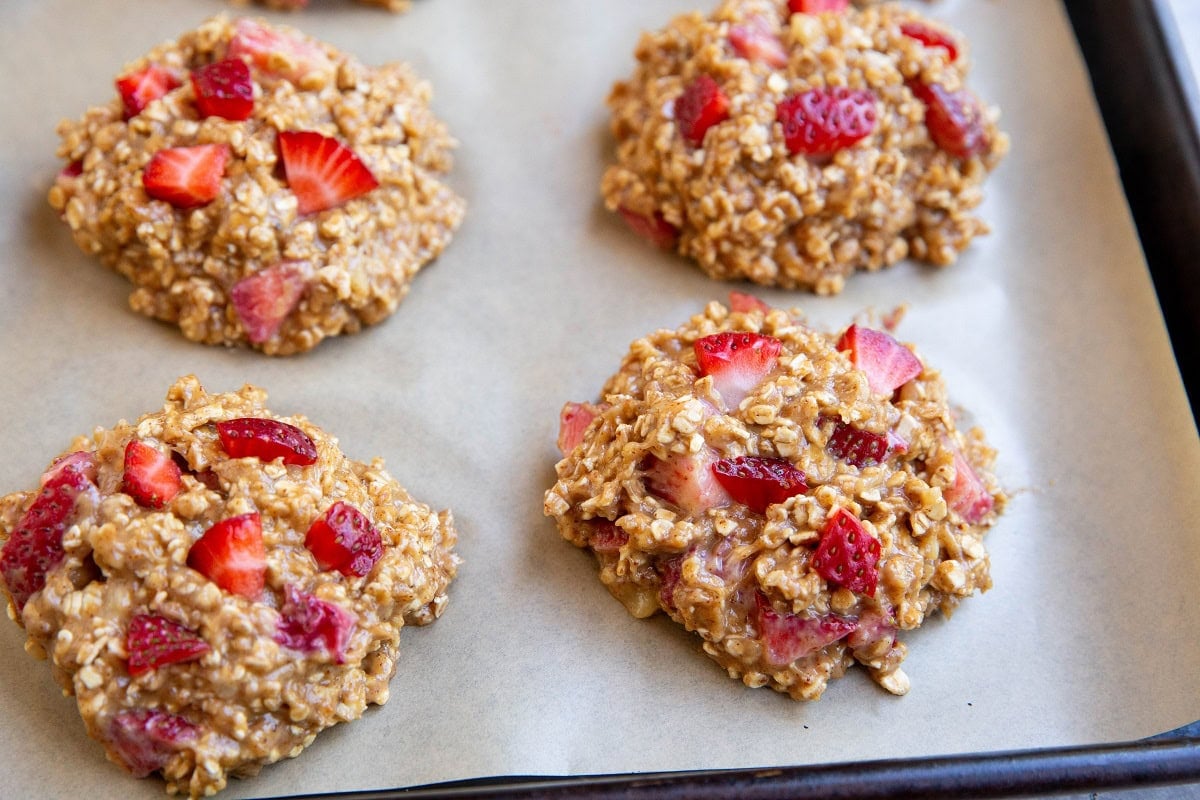 Parchment lined cookie sheet with strawberry oatmeal cookie dough, ready to go into the oven.