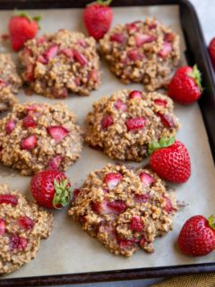 Baking sheet full of strawberry cookies with fresh strawberries all around.