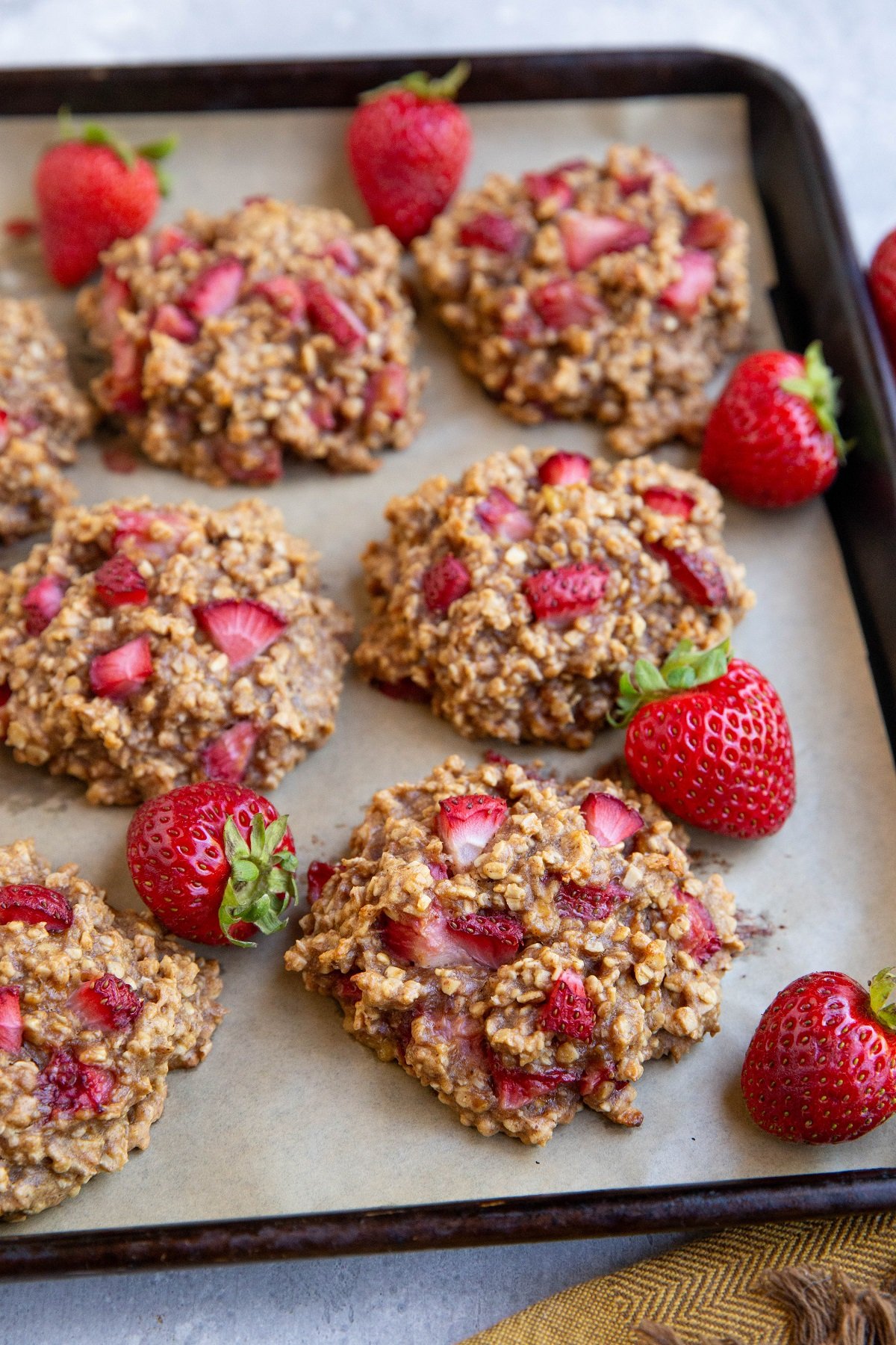 Baking sheet full of strawberry cookies with fresh strawberries all around.