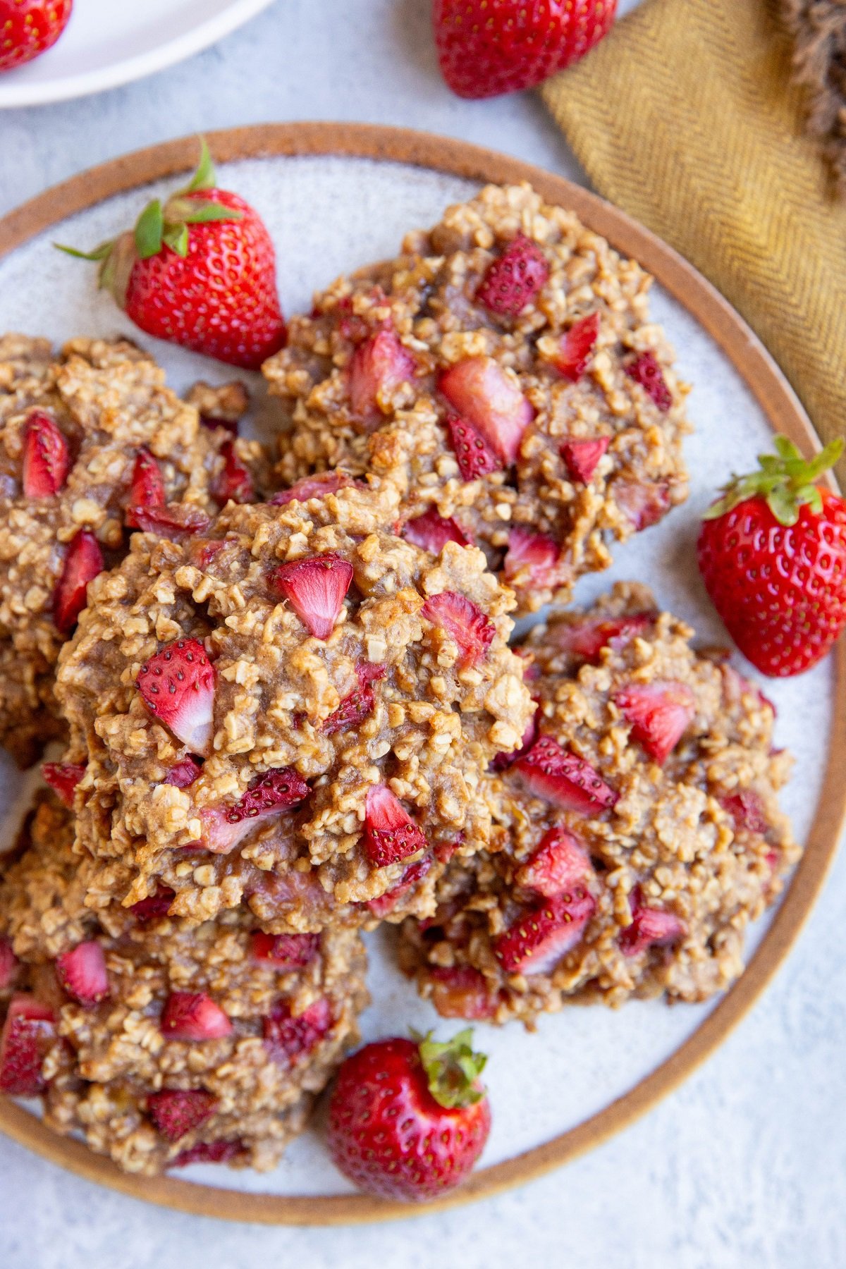 Plate of healthy strawberry cookies with a napkin to the side and fresh strawberries all around.