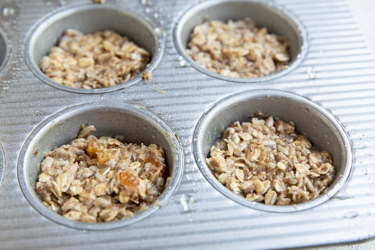 Aussie bite mixture in a sprayed muffin tin, ready to be baked.